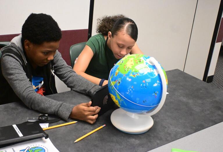 Two students looking at globe together