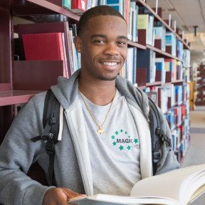 college student wearing backpack and holding book